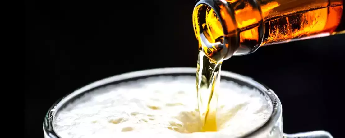 Waarom schuimt bier minder als je het glas schuin houdt?