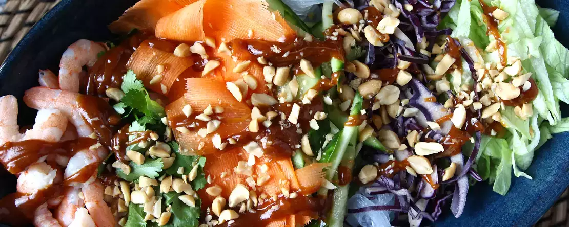 Kleurrijke salade met rijstvermicelli en garnalen en een pittige pindasaus