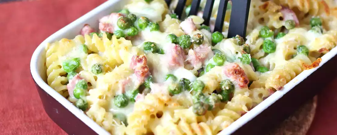 Romig gebakken pasta met erwten en gegratineerde ham