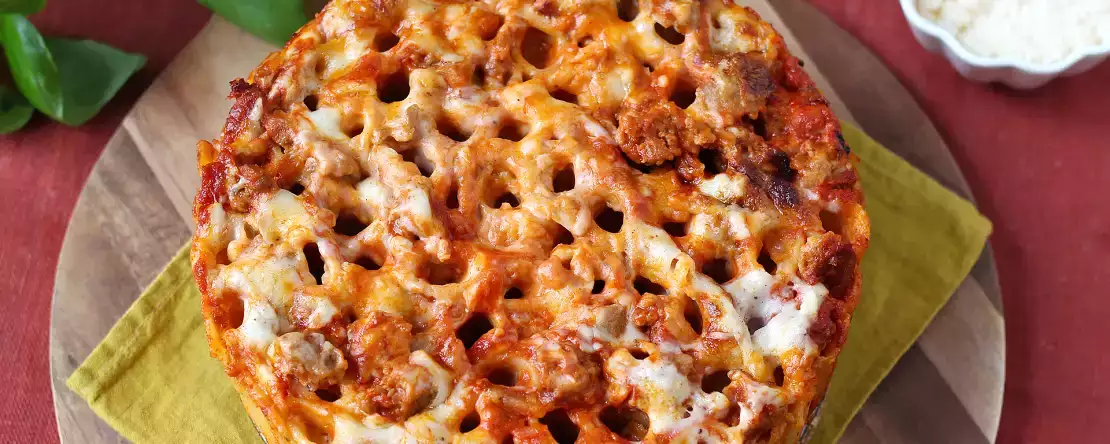 Ovengebakken rigatoni-timballo met worst, bechamelsaus en mozzarella